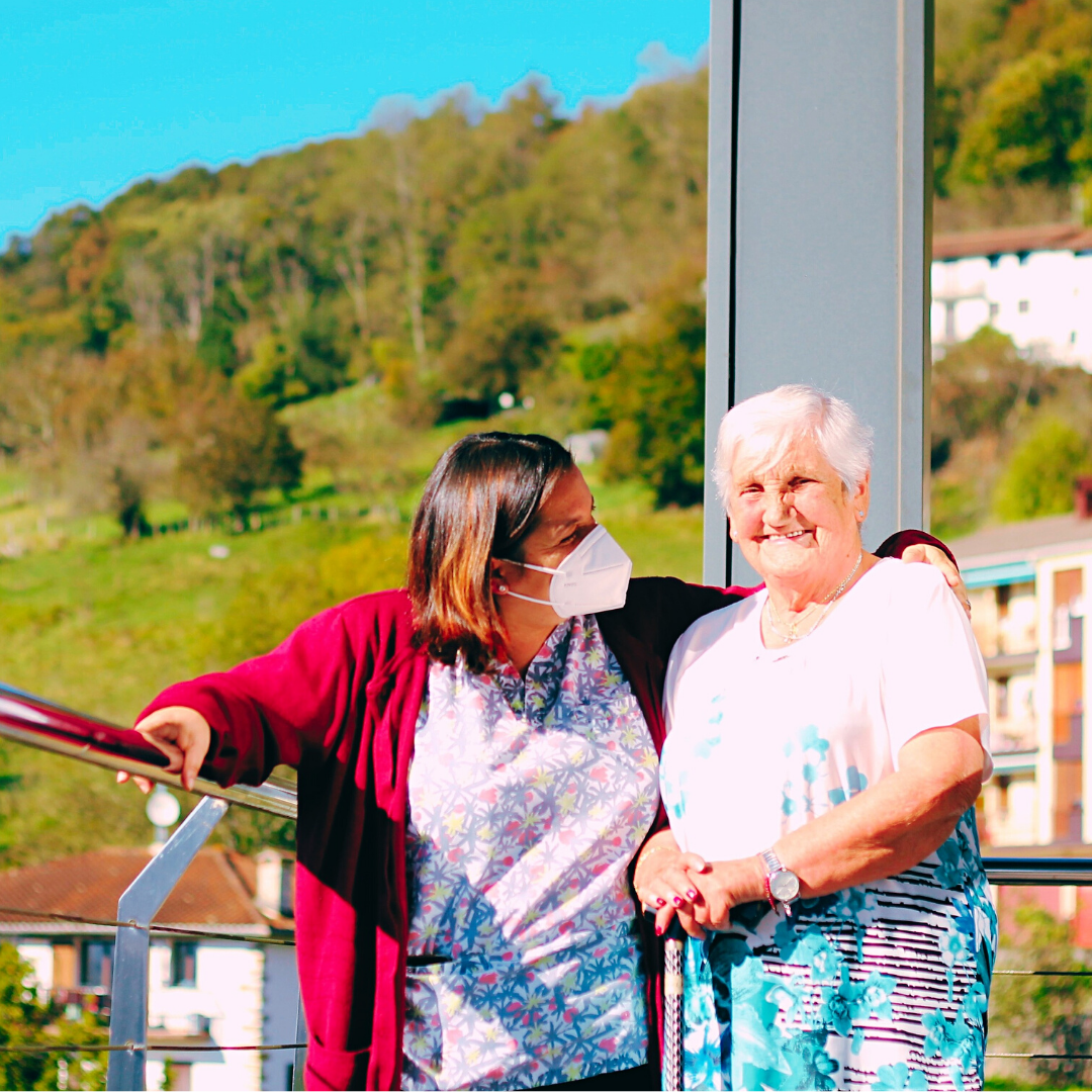 Terapeuta ocupacional y una mujer mayor a la que acompaña disfrutan de la terraza