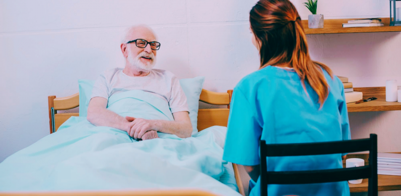 Persona mayor en cama atendido por enfermera