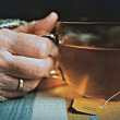 Imagen de una mano de una persona mayor asiendo una taza de té