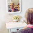 Mujer mayor se mira al espejo mientras su cuidadora sonríe
