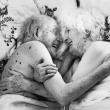 Un hombre y una mujer mayores se miran y sonríen tumbados en la cama