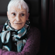 Fotografía de una mujer mayor sentada con una media sonrisa en el rostro