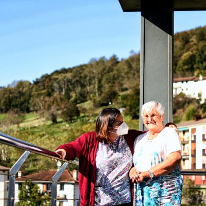 Mujer mayor y su cuidadora disfrutan del paisaje de una terraza